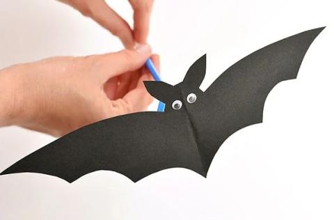 A cut-out of a paper bat on a straw. 